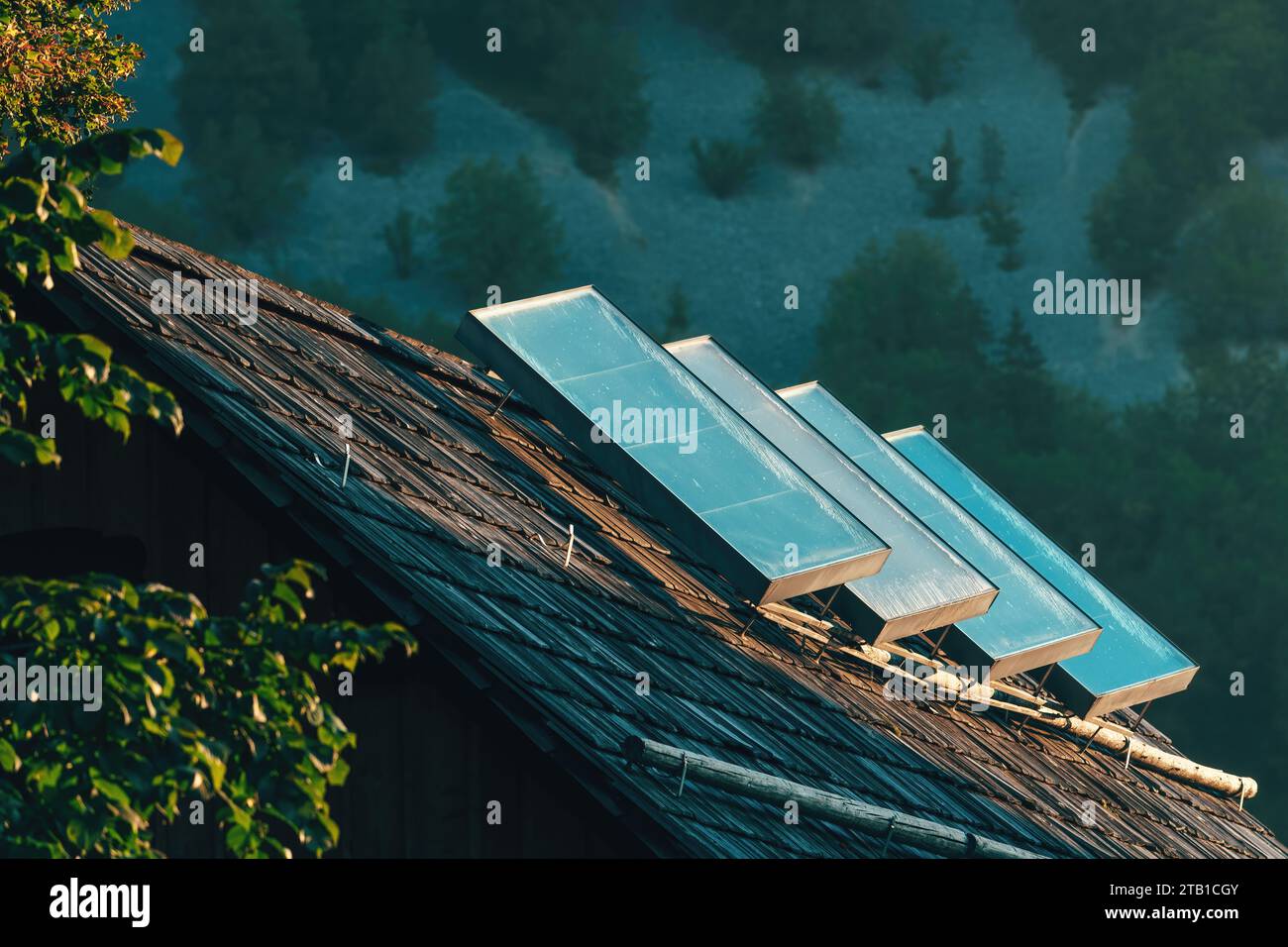 Vecchi pannelli solari di riscaldamento ad acqua sul tetto della casa nella campagna alpina, messa a fuoco selettiva Foto Stock