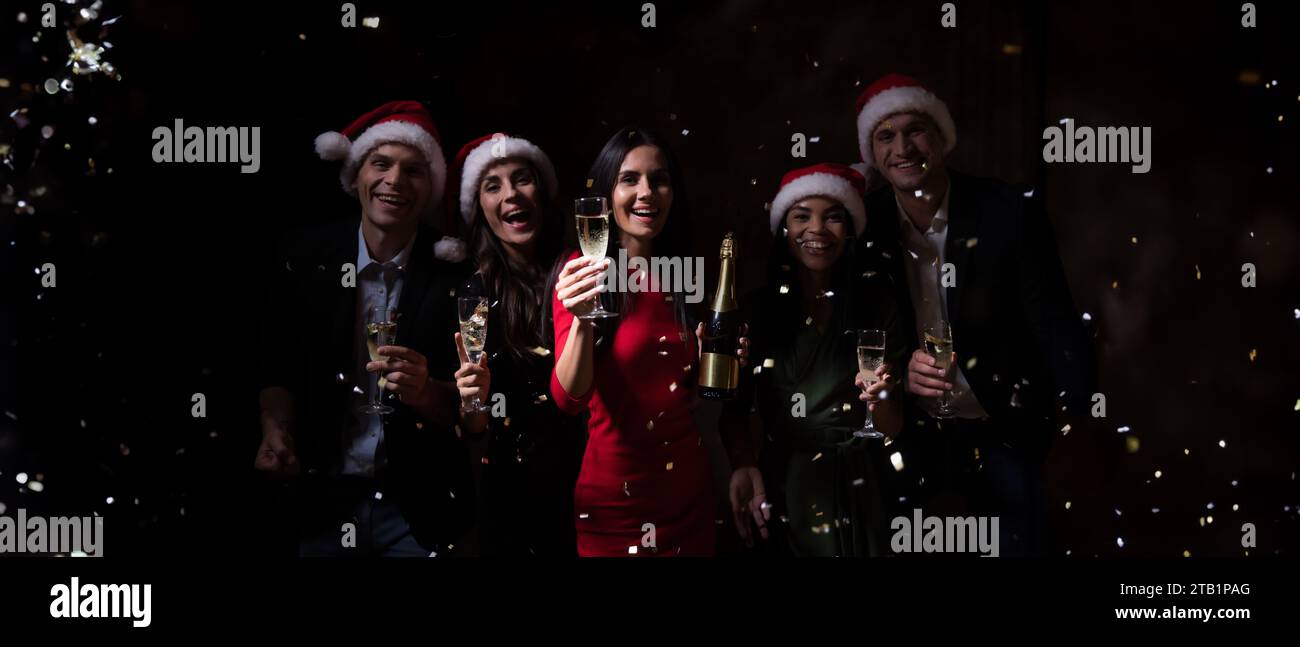 Allegro e divertente gruppo di amici o colleghi mentre festeggiano e ballano, bevono champagne o vino alla festa di Natale o alla vigilia di Capodanno. Corpo Foto Stock