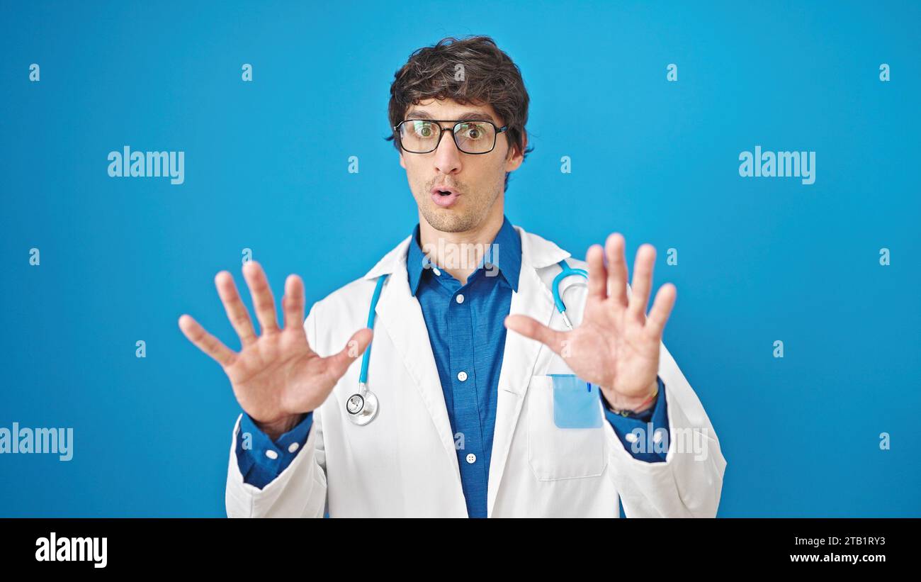 Giovane medico ispanico che fa un gesto calmo su sfondo blu isolato Foto Stock