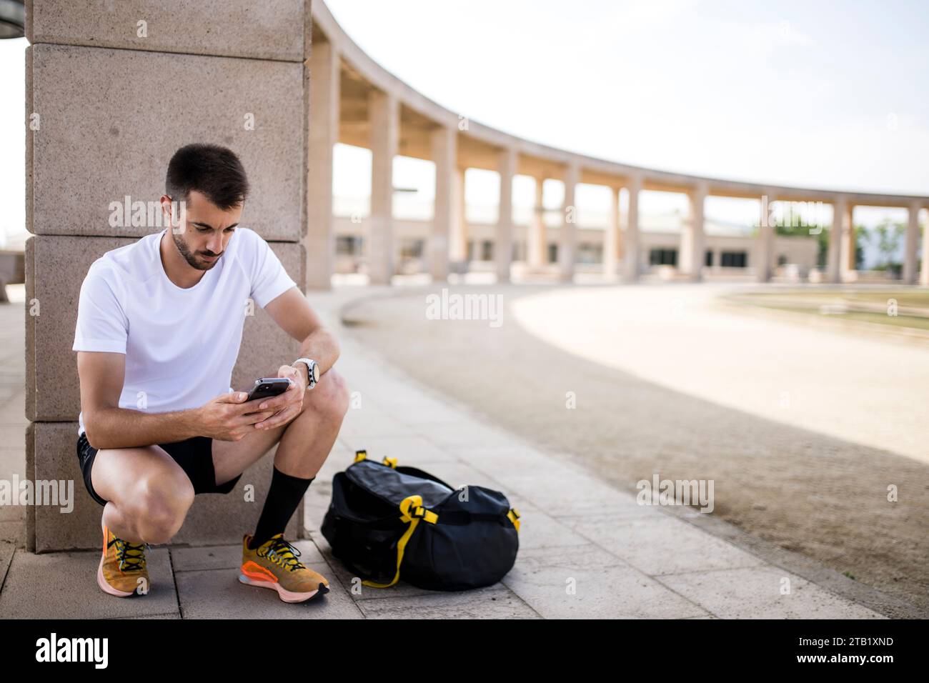Giovane atleta che scrive con una borsa sportiva. Foto Stock