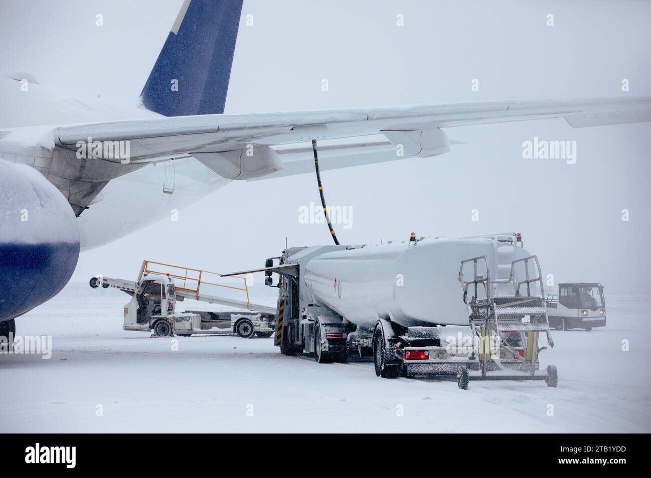 Rifornimento di aeroplano da una autocisterna all'aeroporto durante le nevicate. Servizio a terra prima del volo in una gelida giornata invernale. Foto Stock