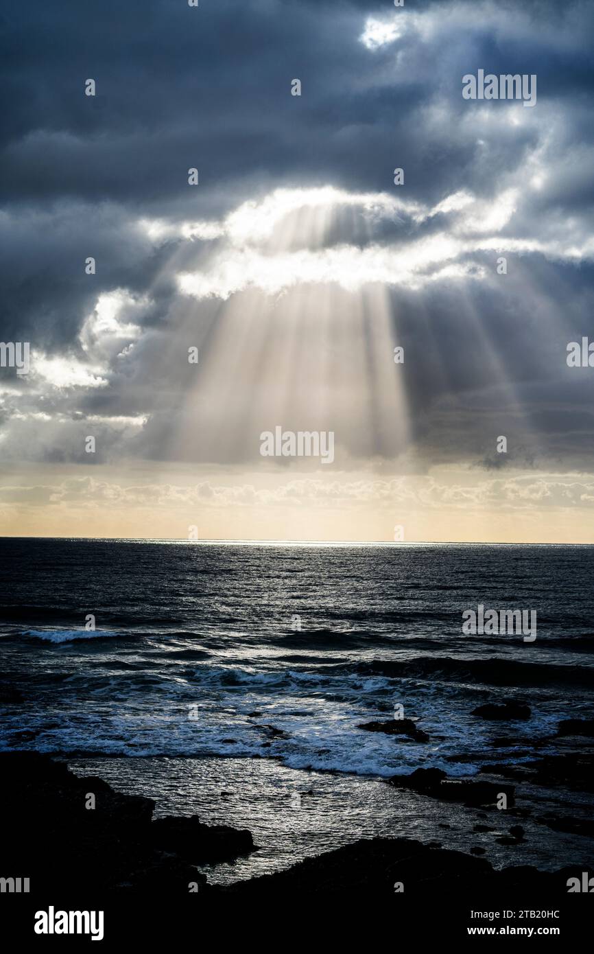 Raggi di sole che brillano attraverso nuvole di tempesta sull'oceano. Foto Stock