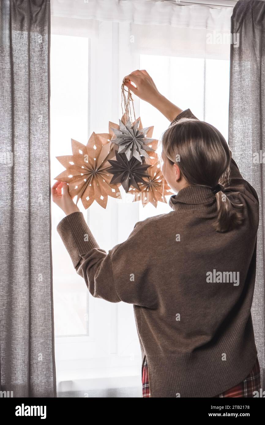Donna che decora la casa di natale con le stelle del mestiere di carta.ambiente accogliente Foto Stock
