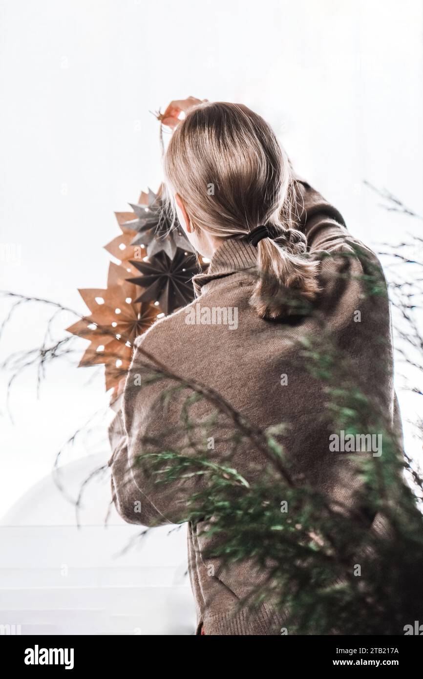 Donna che decora la casa di natale con le stelle del mestiere di carta.ambiente accogliente Foto Stock