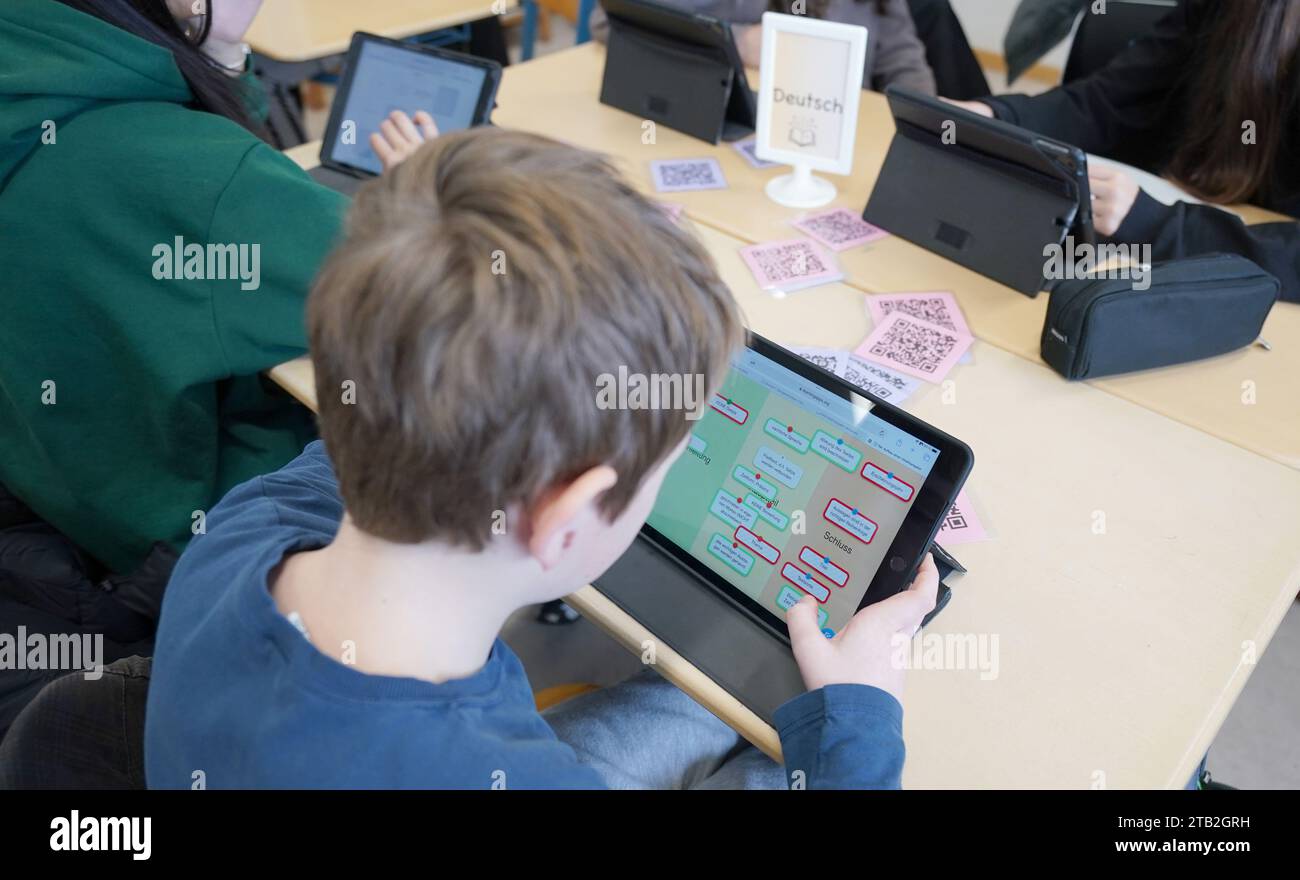 Amburgo, Germania. 4 dicembre 2023. Gli allievi lavorano su un tablet durante il tempo di apprendimento "Fit" (formazione individuale) nella classe 7d presso la Lessing-Stadtteilschule di Harburg-Wilstorf. La senatrice della scuola Rabe ha presentato il progetto modello con scuole completamente attrezzate in digitale presso la Lessing-Stadtteilschule e ha visitato le lezioni digitali nei gradi 5, 6 e 7. Da ottobre, i 1.350 alunni sono stati equipaggiati con iPad. Credito: Marcus Brandt/dpa - ATTENZIONE: Solo per uso editoriale in relazione ai rapporti correnti e solo con riferimento completo al suddetto Credit/dpa/Alamy Live News Foto Stock