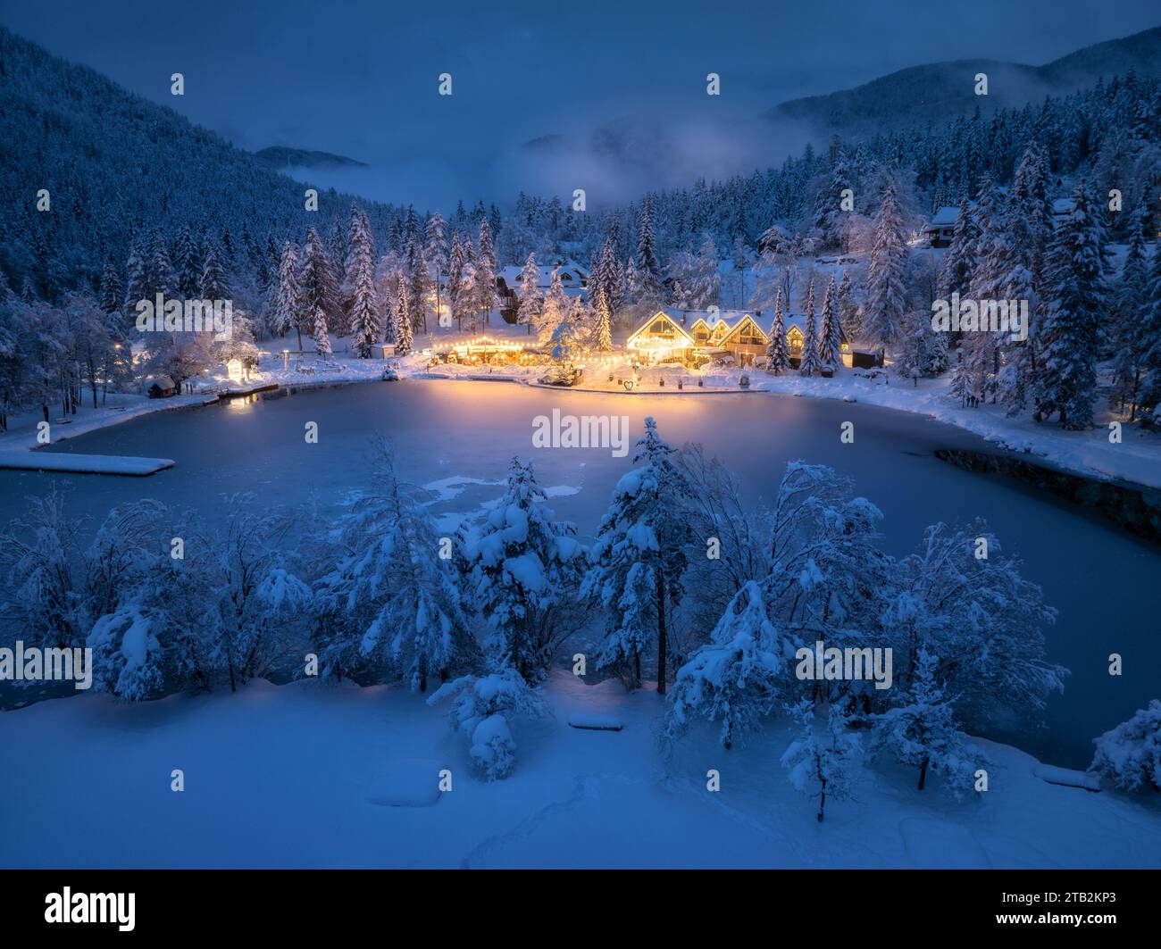 Vista aerea delle case illuminate nel villaggio innevato di notte Foto Stock