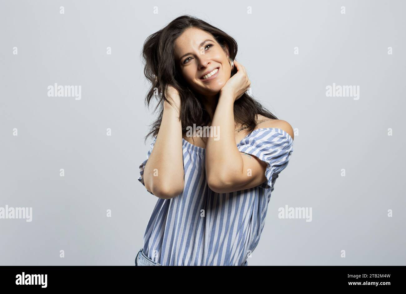 Bella e sorridente donna bruna che guarda in alto, isolata su sfondo grigio Foto Stock