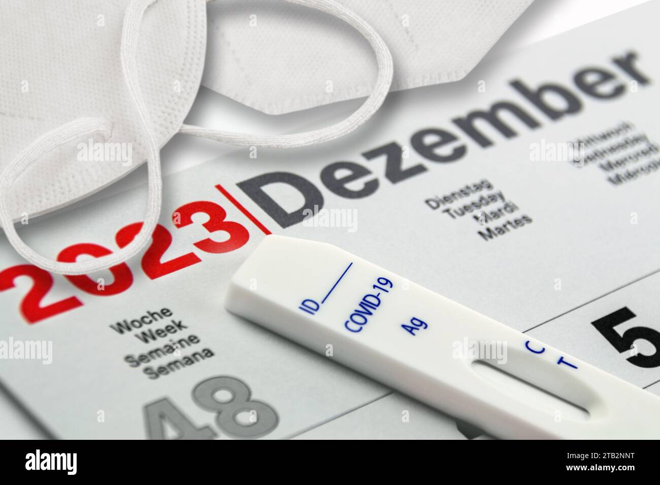 Corona Pandemie und Deutscher Kalender Dezember 2023 mit Covid-19 Antigen test Schnelltest und Maske Foto Stock