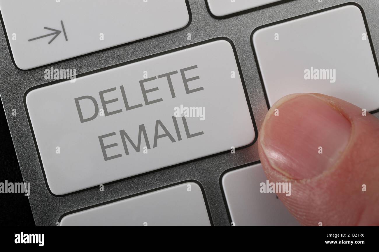 Un uomo che preme un pulsante di eliminazione e-mail sulla tastiera del compter. Foto Stock