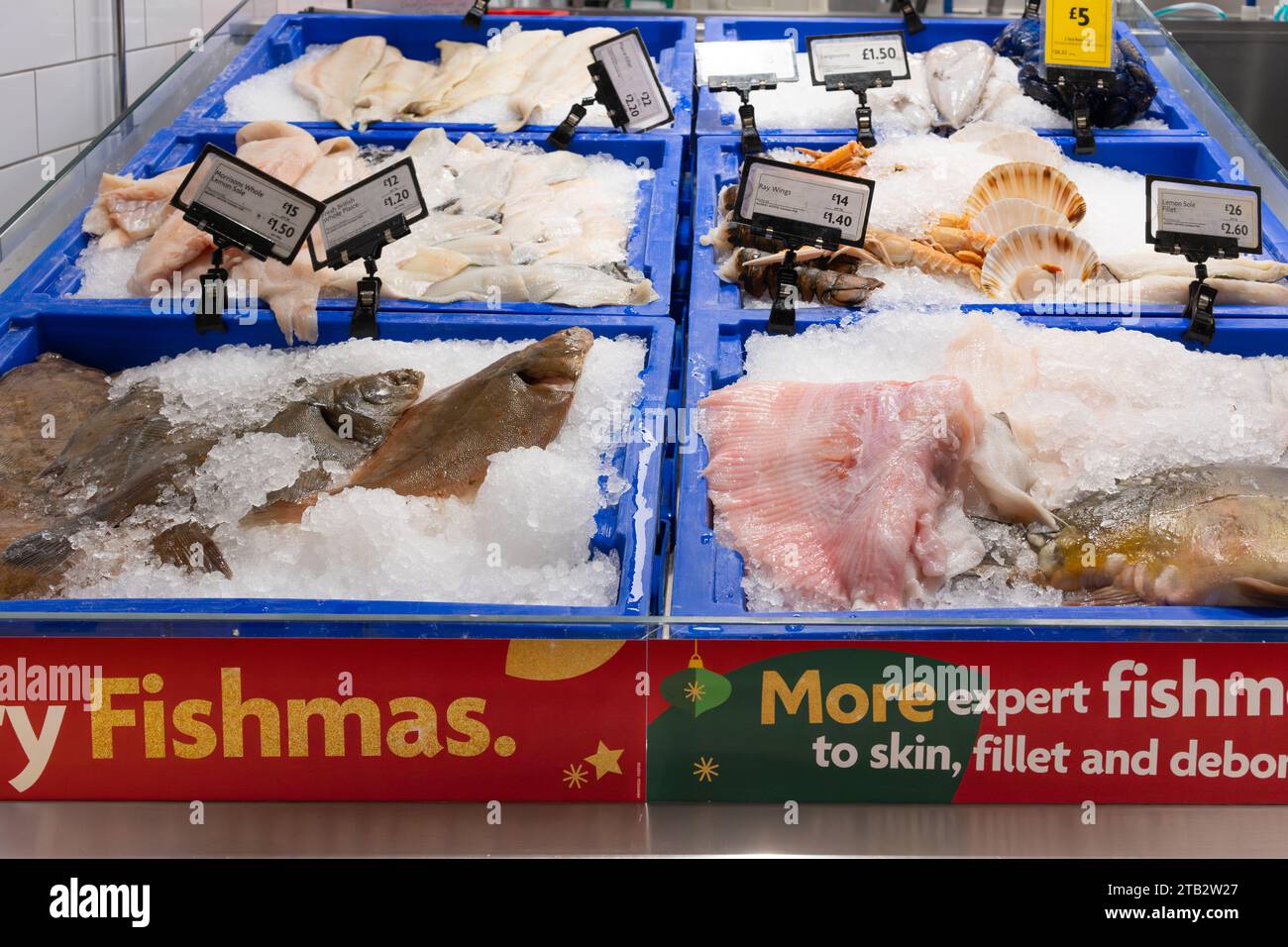 Banco di pesce fresco al supermercato Morrisons con ali di razze, passera di mare intera, sogliola al limone e capesante in vendita. REGNO UNITO Foto Stock