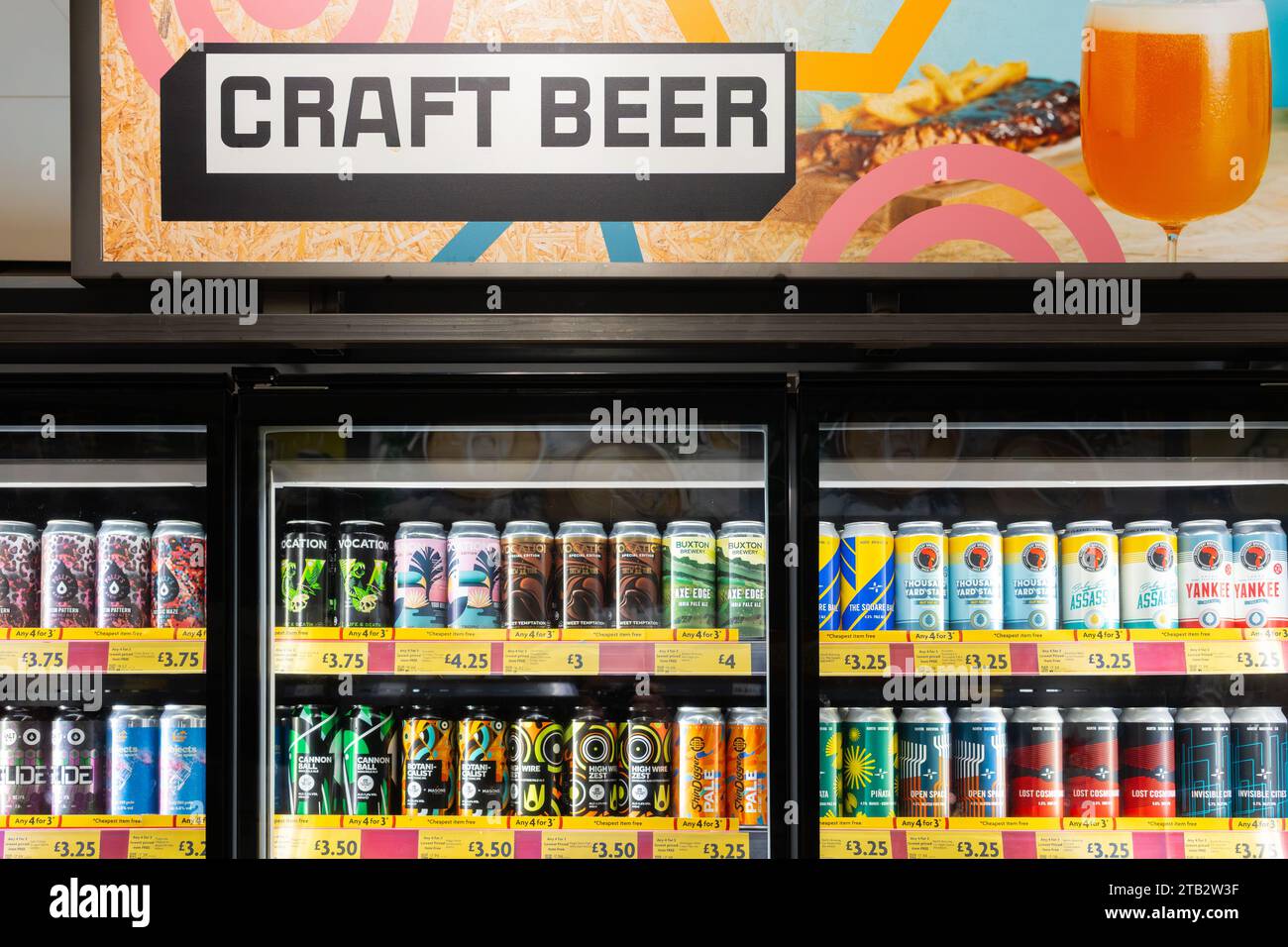 Una vasta collezione di birre artigianali fredde in lattine, con un cartello pubblicitario sulla birra artigianale sopra, in frigoriferi in vendita al supermercato Morrisons, in Inghilterra Foto Stock