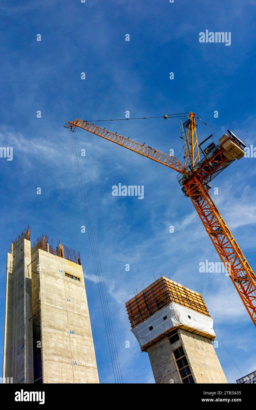 Alti edifici in costruzione con gru e cielo blu sullo sfondo. Foto Stock