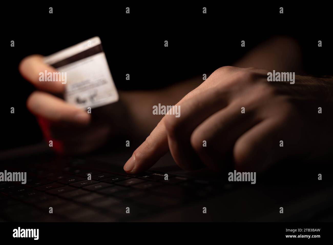 Uomo che digita i dati della carta di credito su un computer o un computer portatile con una luce rossa. Foto Stock