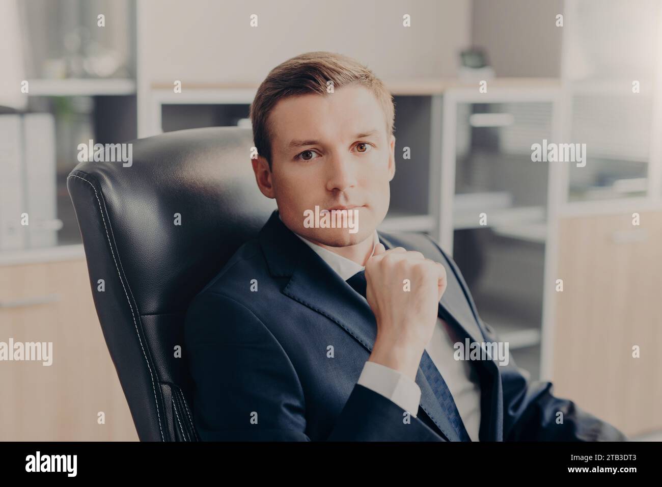 Dirigente di sesso maschile sicuro di sé con uno sguardo concentrato seduto alla scrivania dell'ufficio Foto Stock