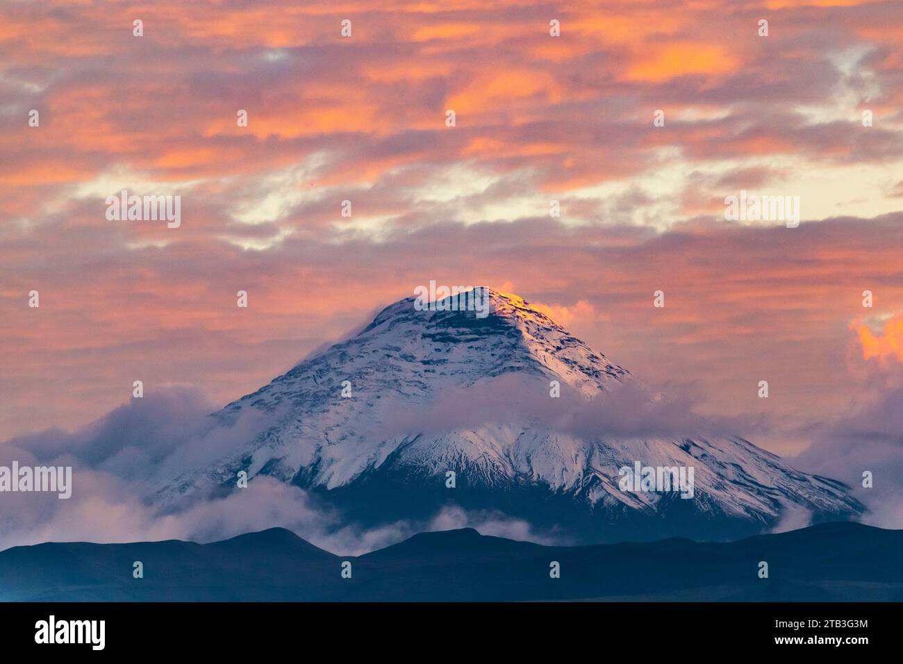 Vulcano Cotopaxi al tramonto con nuvole in blu e rosso viste da Quito, Ecuador Foto Stock