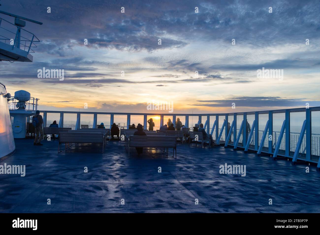 I turisti che si godono lo splendido tramonto di Orange visto da un traghetto tra la Danimarca e l'Islanda nell'Oceano Atlantico Foto Stock