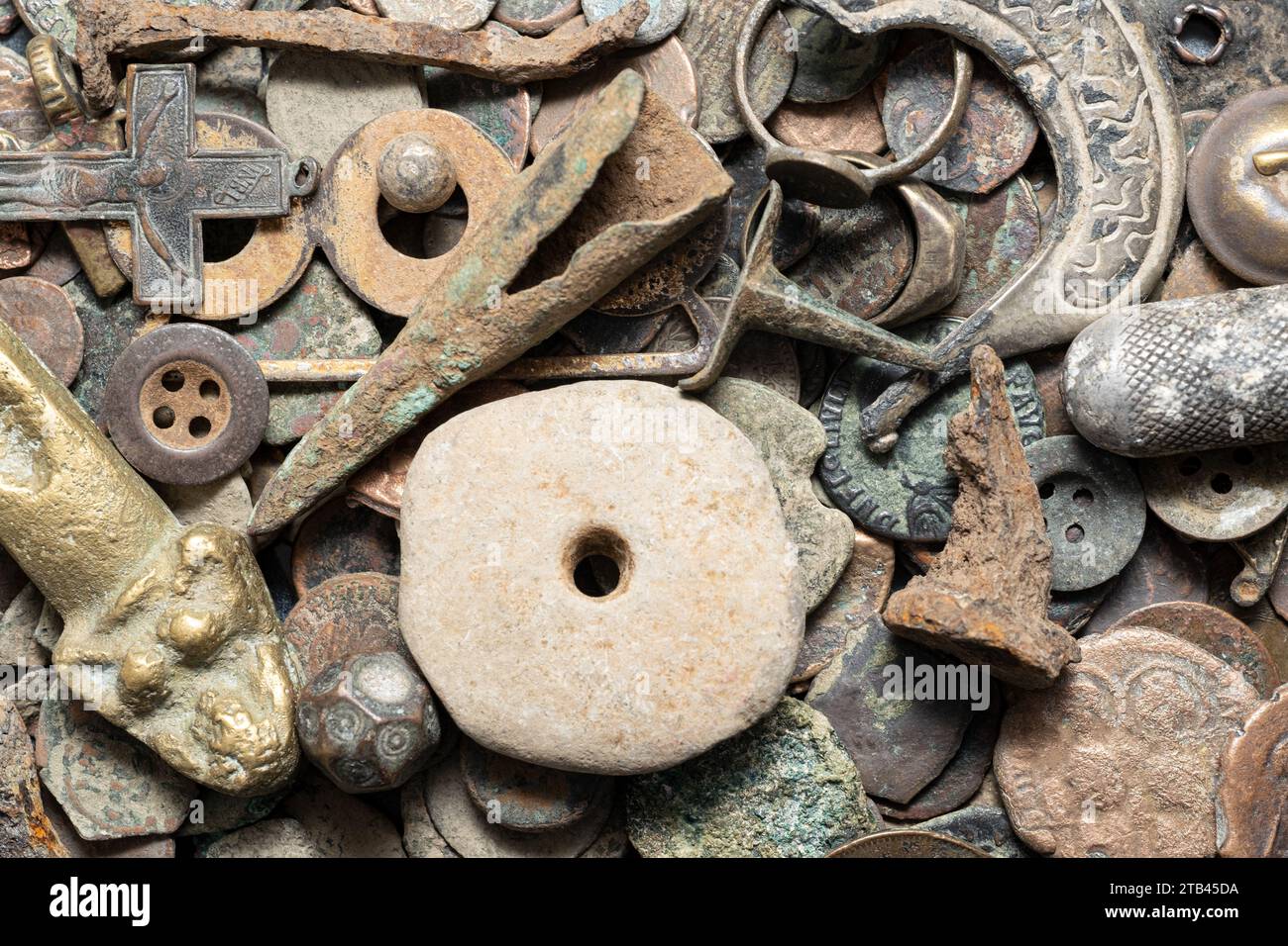 Una collezione di antiche reliquie di ferro, comprese monete, punte di freccia, unghie, proiettili, e una croce, manufatti storici del passato di epoche passate. Foto Stock