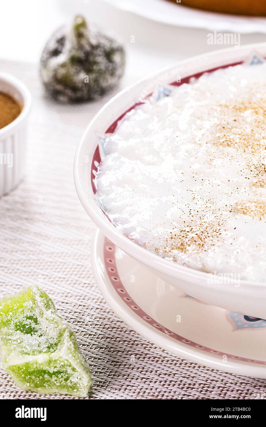 ciotola per budino di riso, budino fatto in casa a base di riso macinato, addolcito con polvere di cannella e corteccia di cannella. Dolci brasiliani rurali in background, Foto Stock