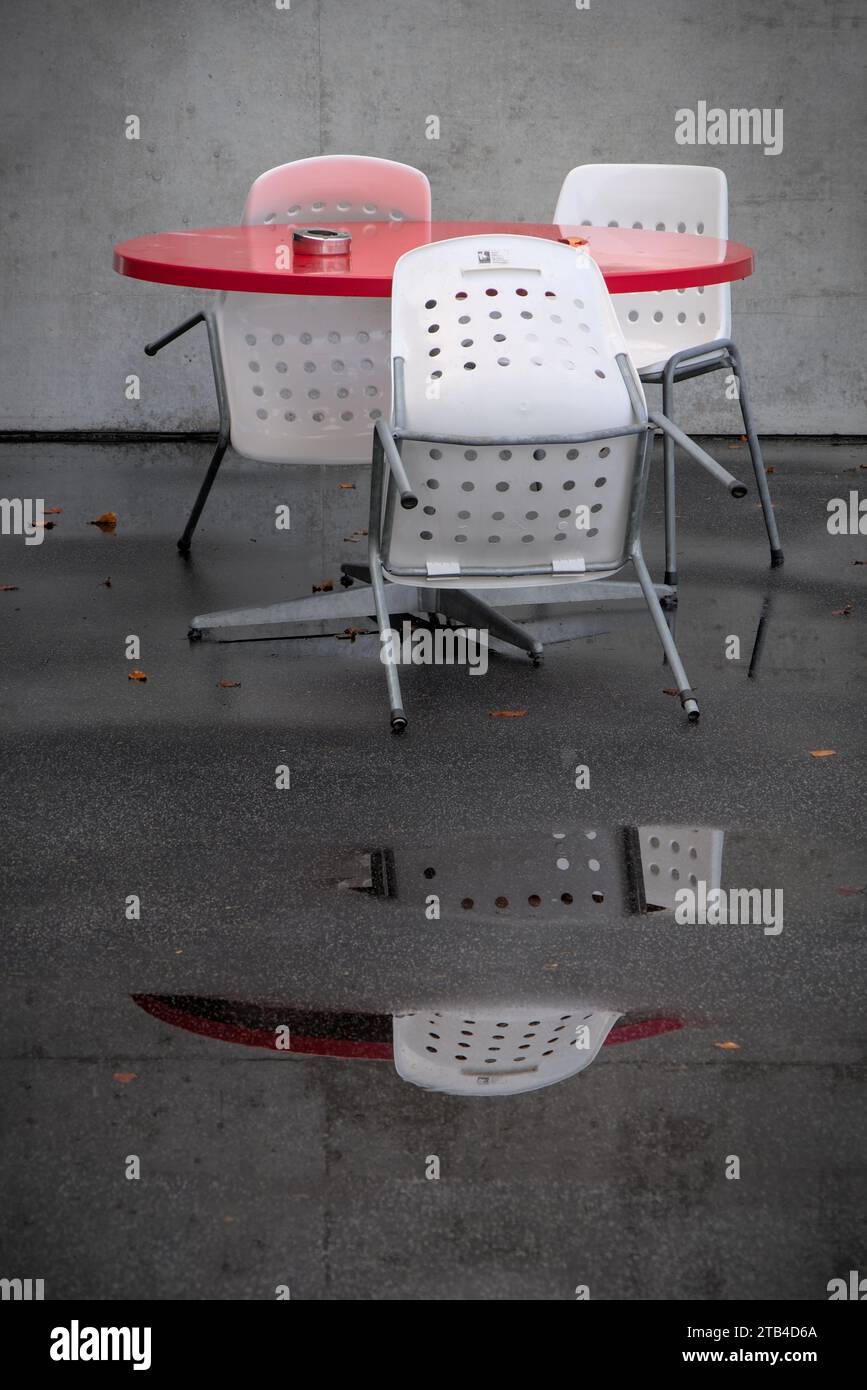 Impressioni di un lido chiuso. Riflessi delle sedie in una pozza in una giornata di pioggia in un bagno pubblico. Foto Stock