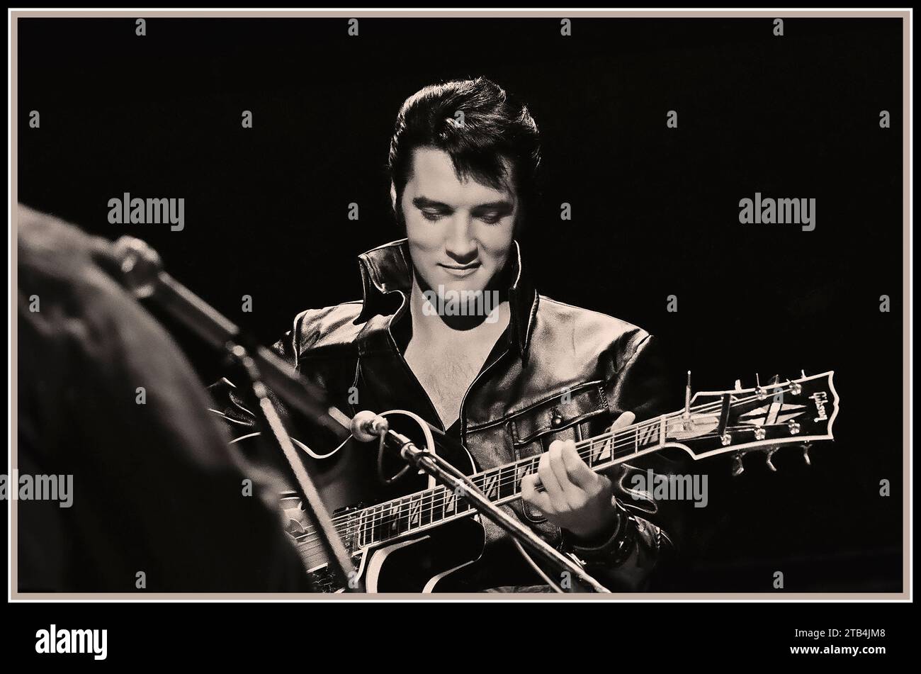 Elvis Presley con la chitarra in uno spettacolo speciale del 1968, che indossa la sua iconica tuta in pelle sul palco Foto Stock
