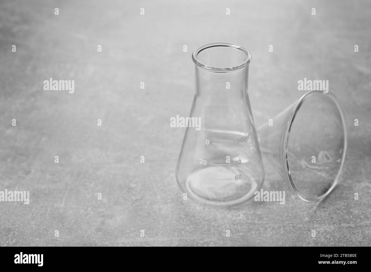 Matraccio e imbuto filtrante su tavolo con superficie grigia, spazio per testo. Vetreria da laboratorio Foto Stock