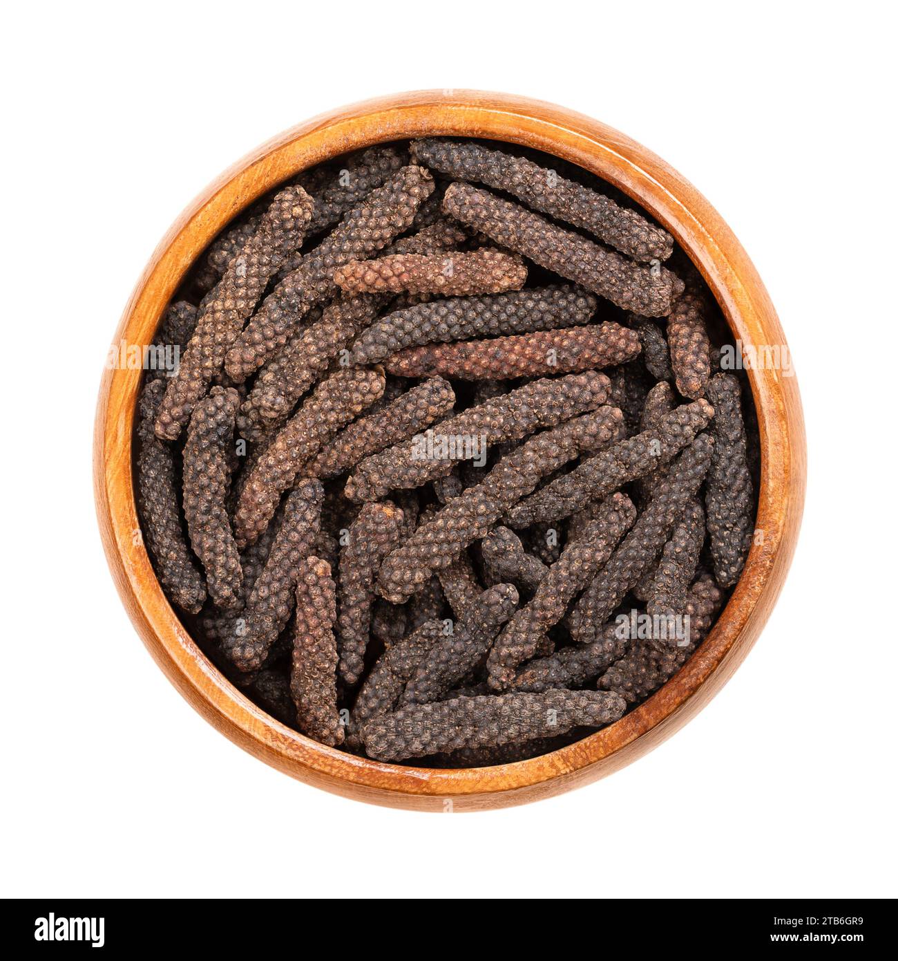 Gattini di pepe lunghi essiccati in un recipiente di legno. Frutti di Piper longum, a volte chiamato pepe lungo indiano o pippali. Utilizzato come spezie e condimenti. Foto Stock