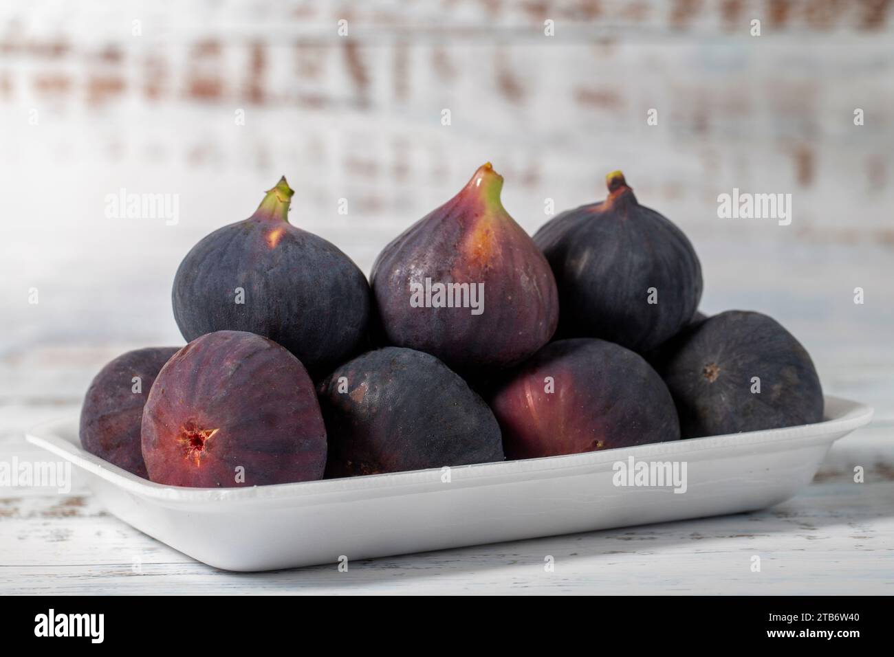 Fichi freschi confezionati su fondo di legno bianco. Prodotti agricoli biologici Foto Stock
