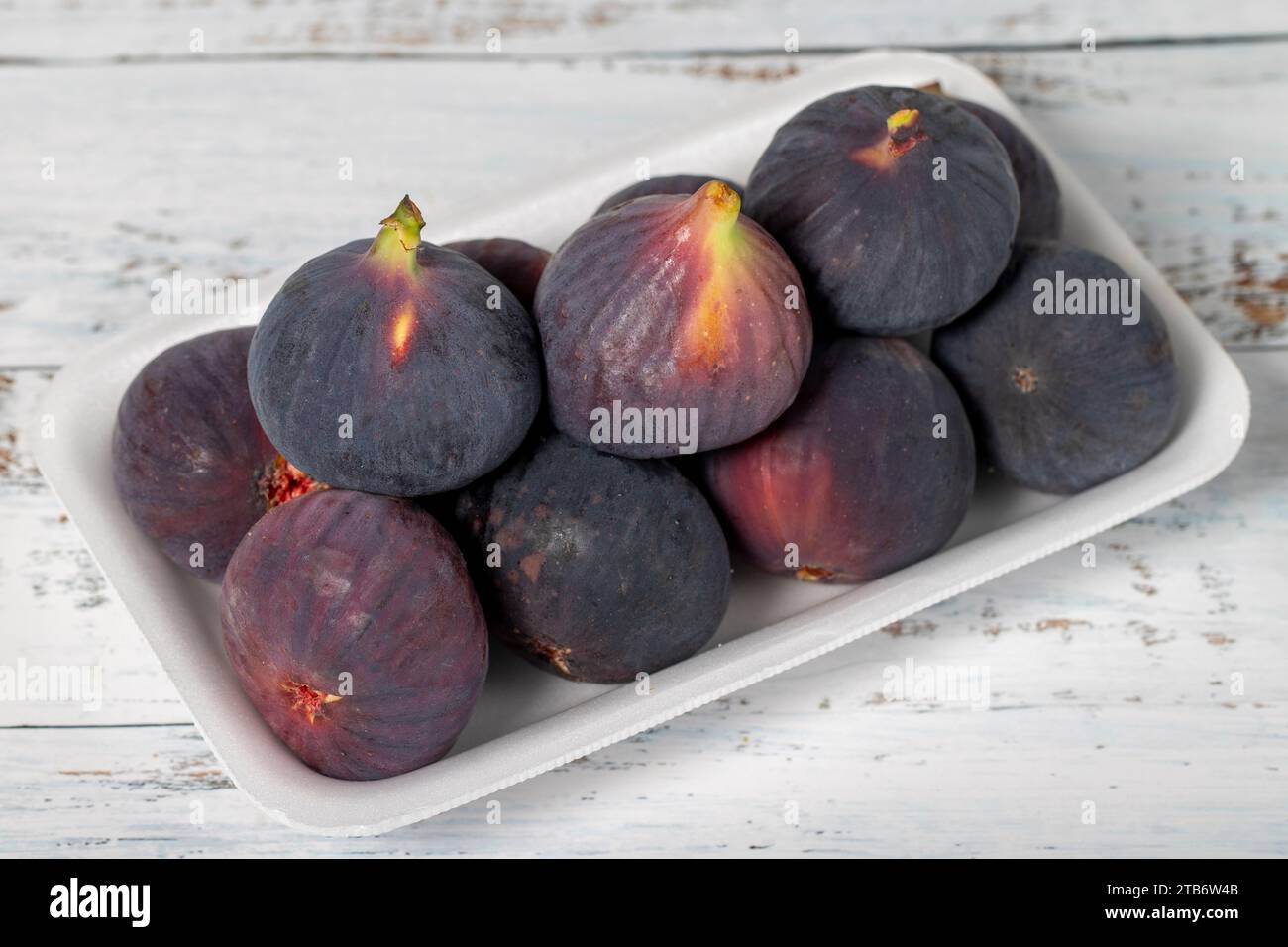 Fichi freschi confezionati su fondo di legno bianco. Prodotti agricoli biologici Foto Stock