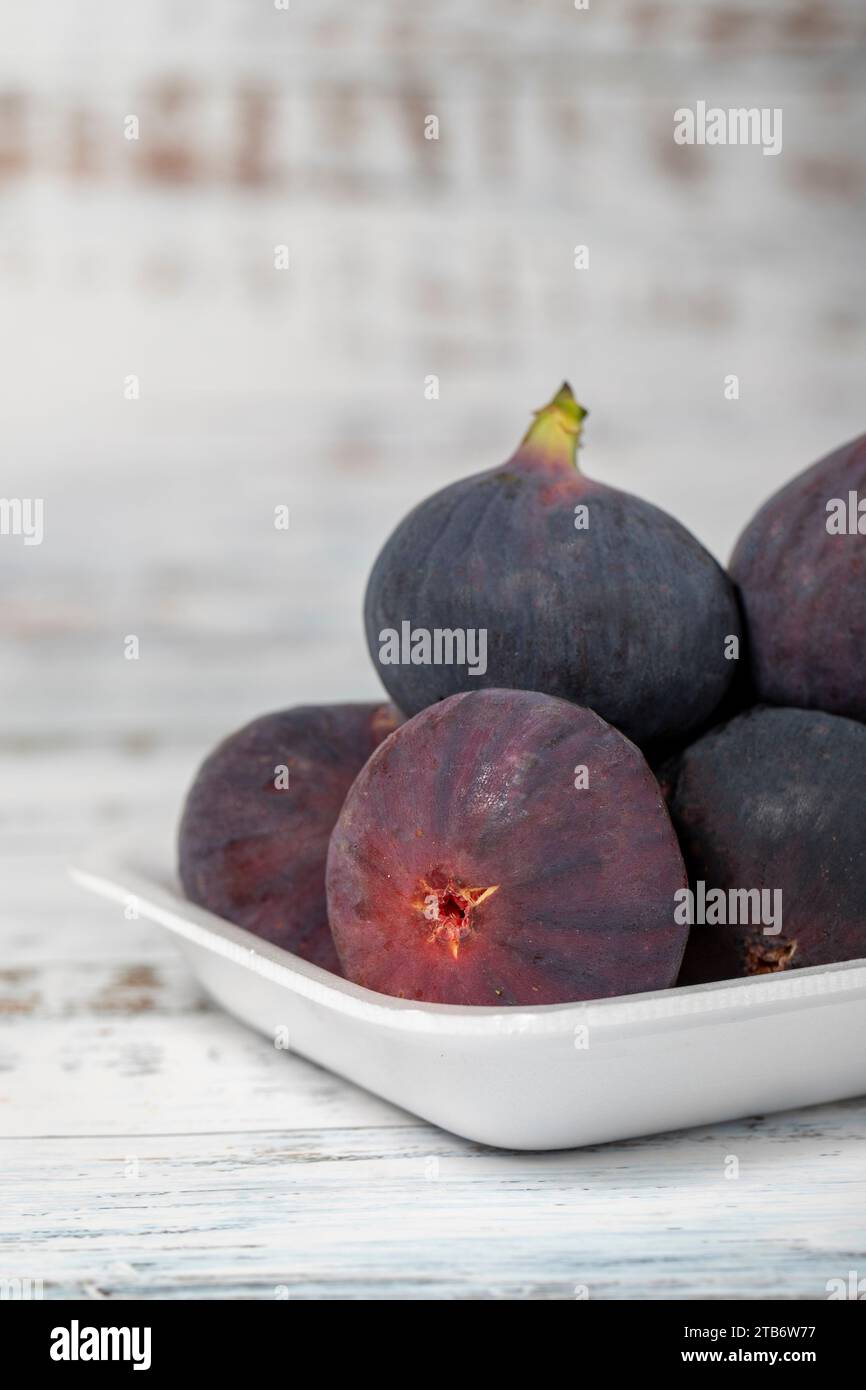 Fichi freschi confezionati su fondo di legno bianco. Prodotti agricoli biologici. Primo piano Foto Stock