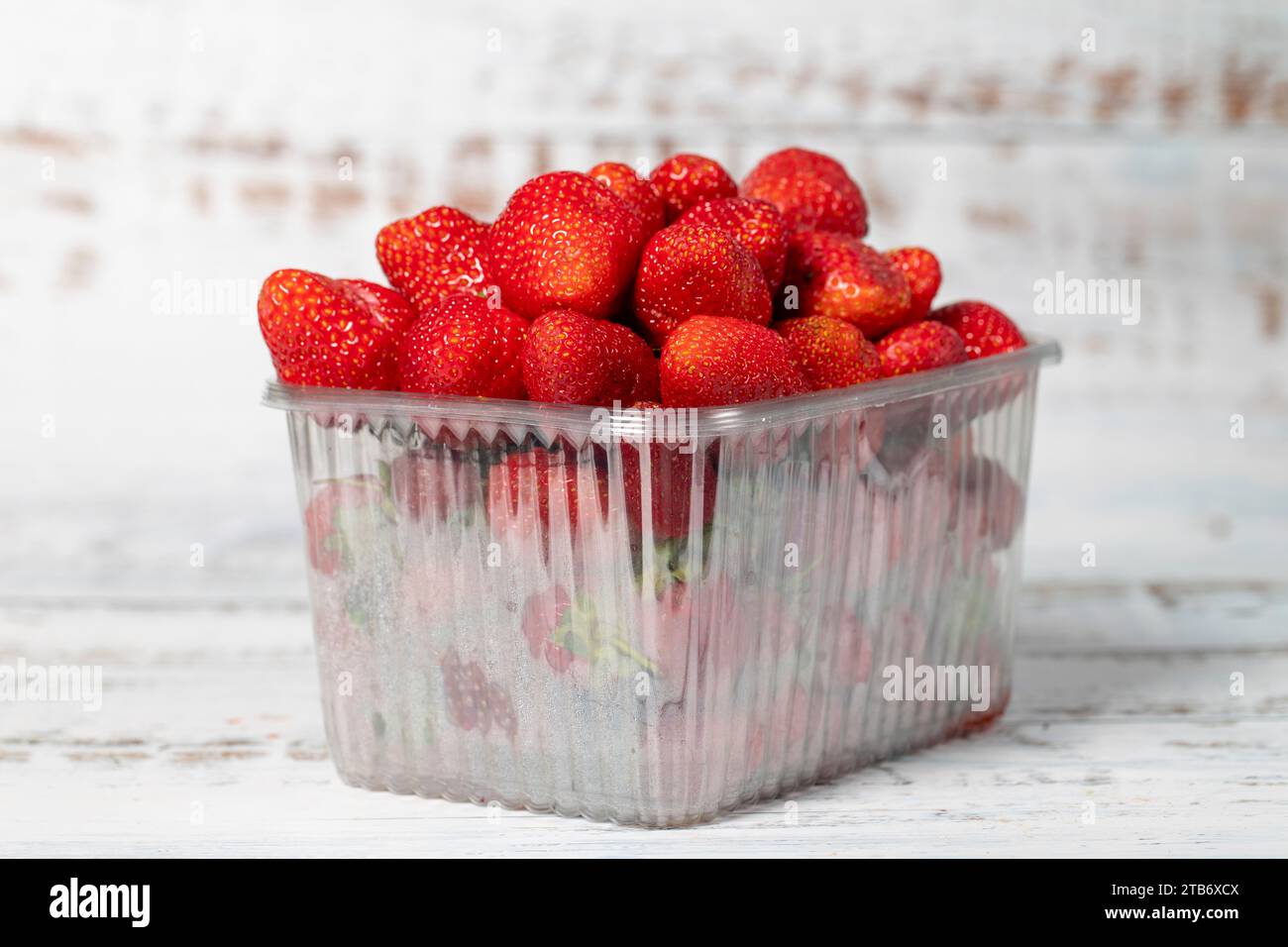 Fragole confezionate su fondo di legno bianco. Prodotti agricoli biologici. Deliziose fragole mature Foto Stock