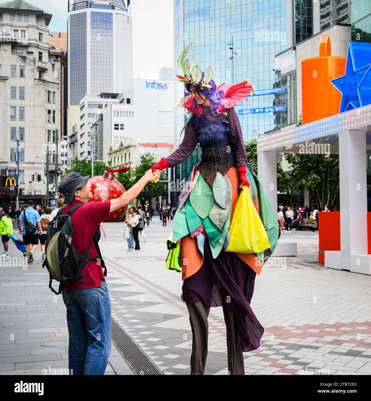 Performer su palafitte che stringono la mano al turista al festival di Natale di Queen Street, nel centro di Auckland. Foto Stock
