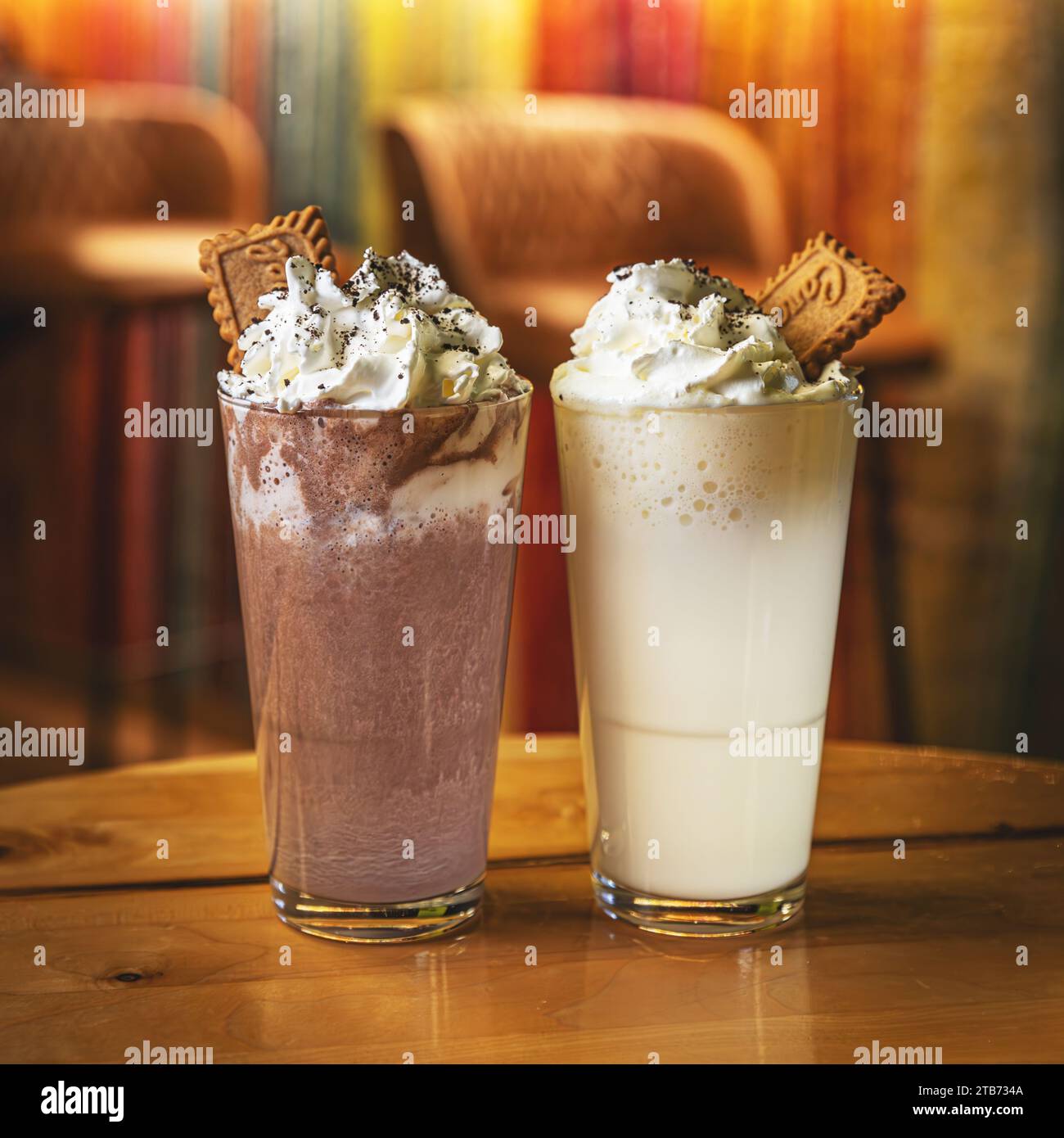 Bicchiere di cioccolato bianco caldo e fondente con panna montata. Bevande cosparse di cacao in polvere e servite con biscotti Foto Stock
