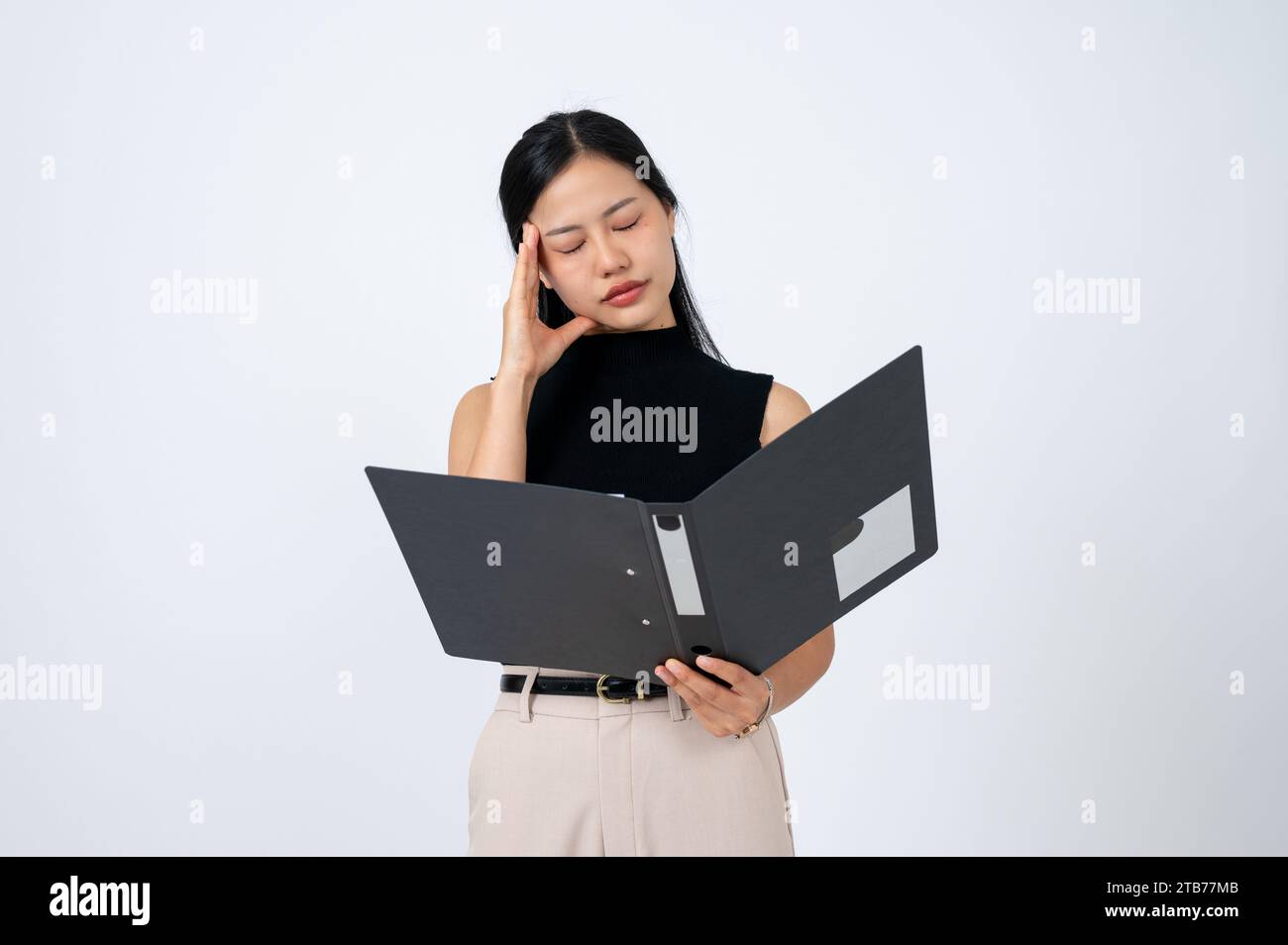 Una donna d'affari asiatica infelice e stanca o un capo donna che legge documenti in un raccoglitore con una faccia delusa e sentendo mal di testa, un bianco isolato Foto Stock