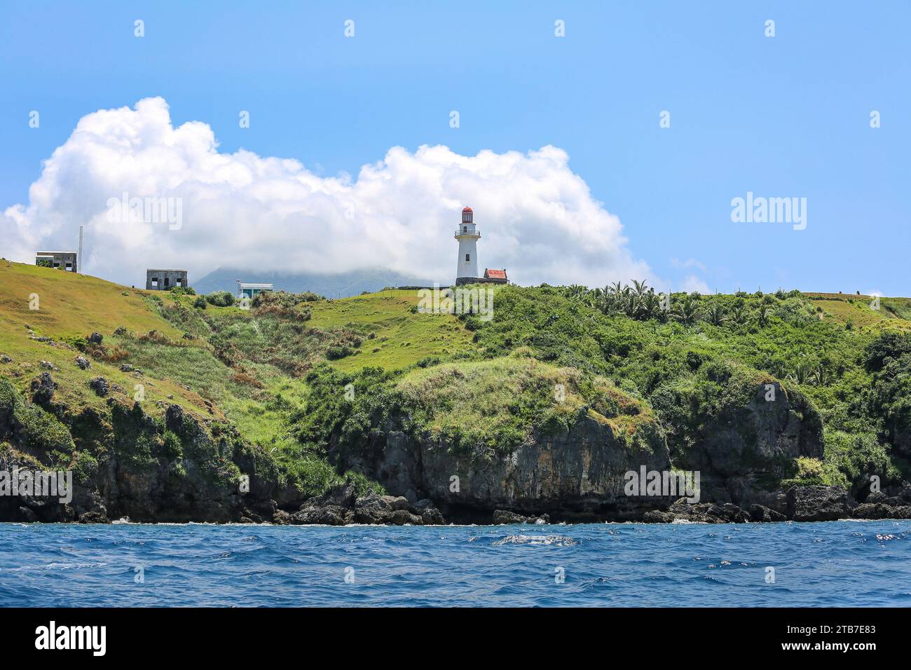 Scogliere di Batanes dal mare, vista sul faro di Basco sulle colline di Naidi, isola di Batan, isole delle Filippine del Nord vicino a Taiwan Foto Stock