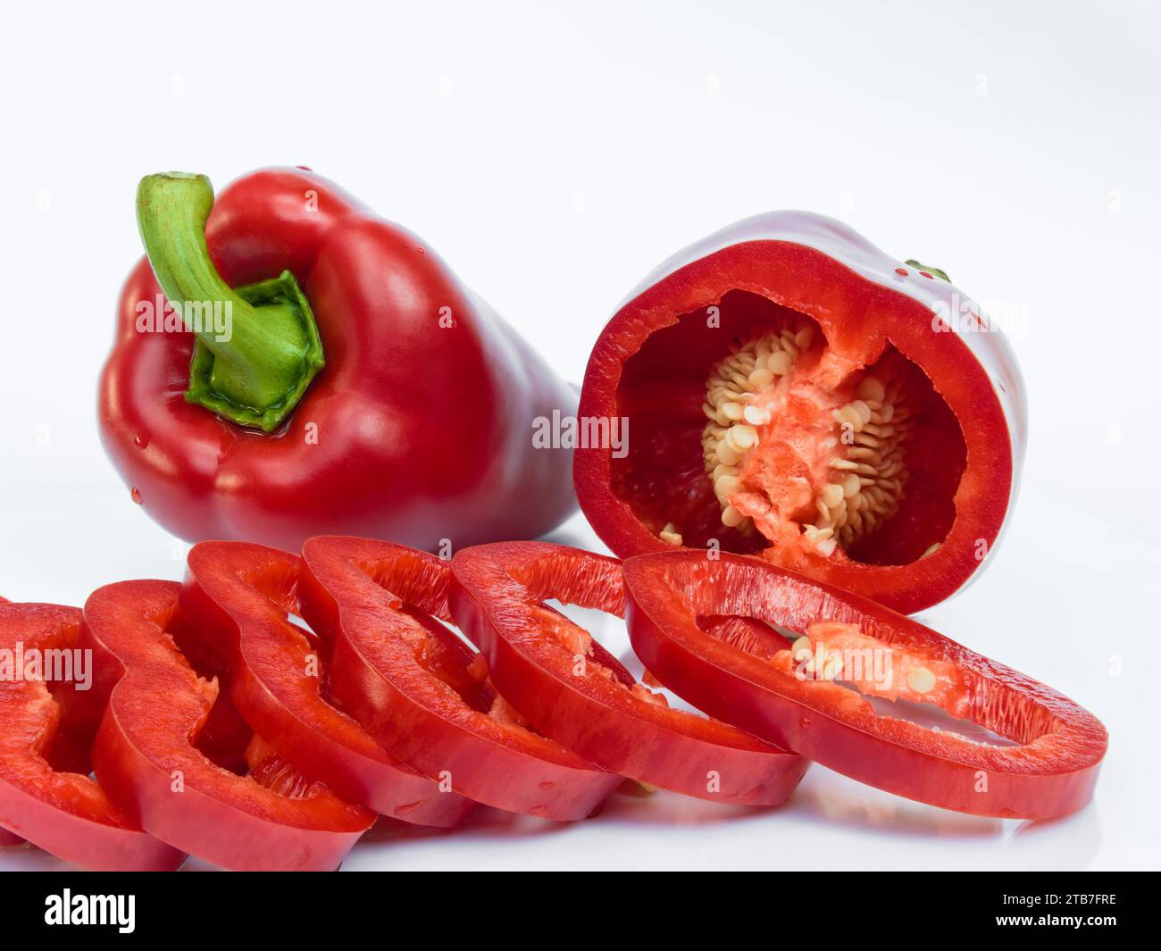 Primo piano del ​​red peperone tagliato a fette (paprika, capsicum) isolato su sfondo bianco con riflesso Foto Stock