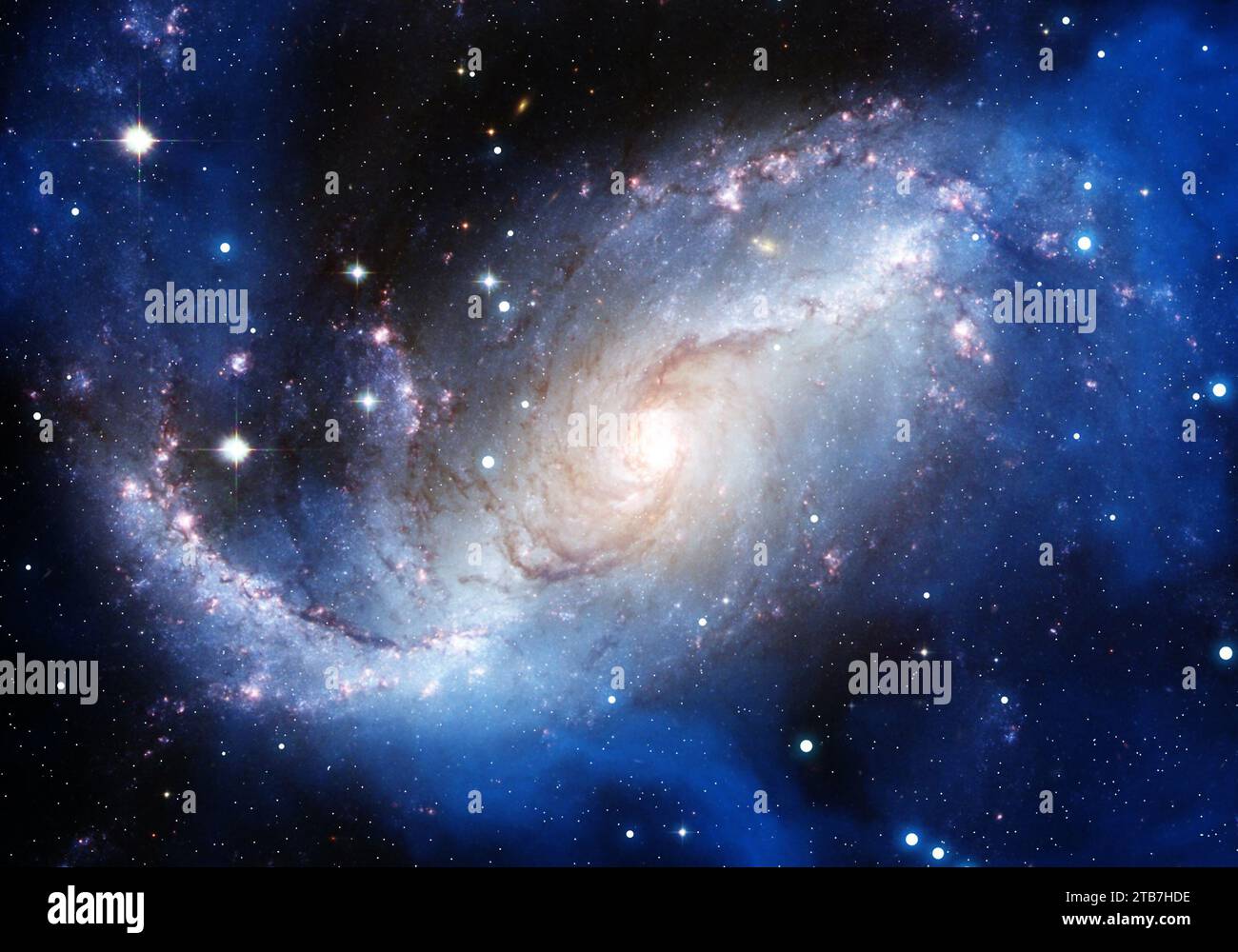 Galassia spirale a faccia vista con un nucleo luminoso brillante, bracci di formazione stellare blu e un campo denso di stelle nello spazio profondo. Foto Stock