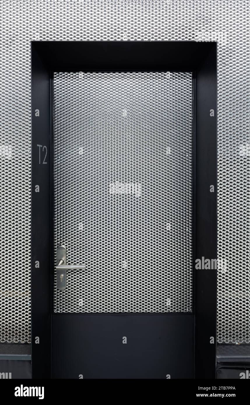 Porta chiusa metallizzata con testo t2 e parete a motivi a griglia bianca nell'attico moderno e contemporaneo Foto Stock