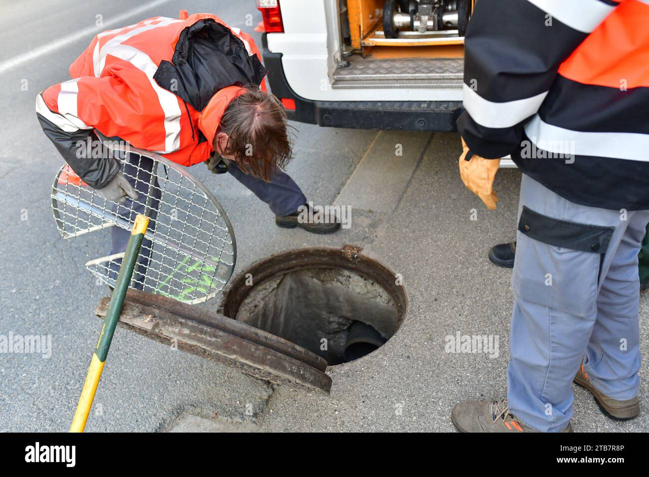 Lione (Francia centro-orientale): Team di lavoratori delle acque reflue che allestiscono il loro sito di ispezione fognaria con telecamere robotizzate sulla carreggiata. Stanno sollevando un tombino co Foto Stock