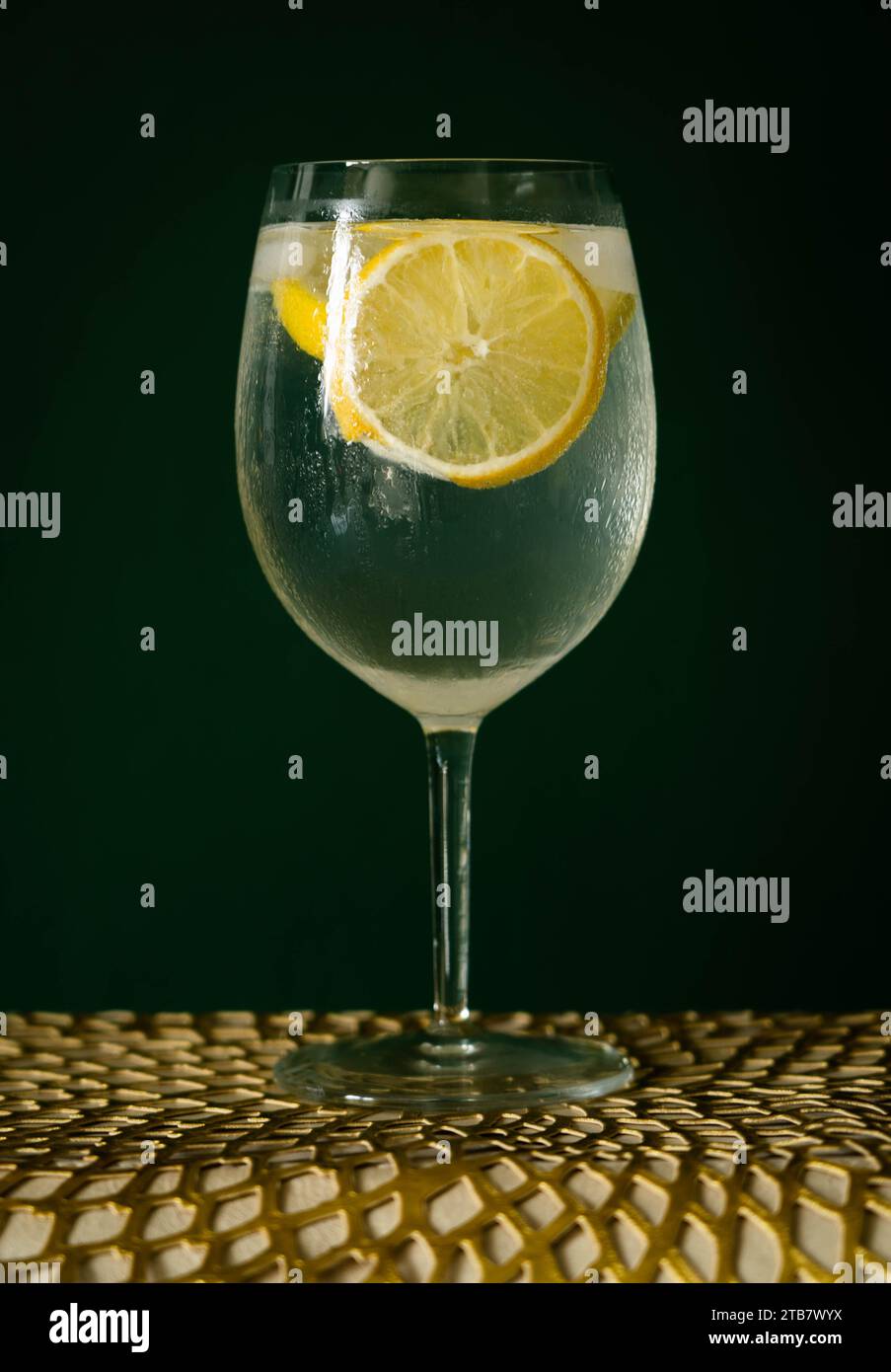 Cocktail gin e Tonic Highball con ghiaccio e limone di fronte a sfondo verde Foto Stock