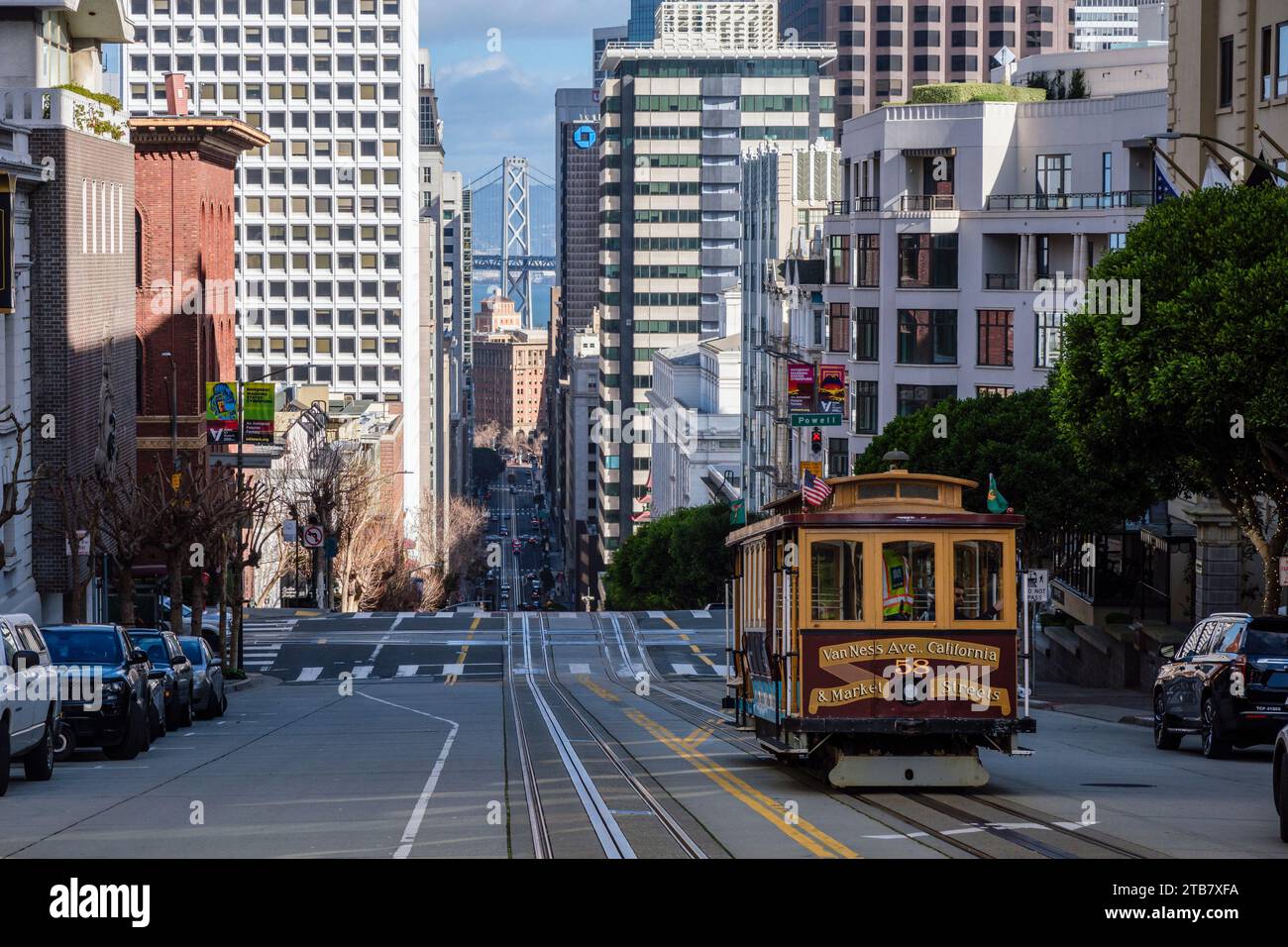 Una funivia che scende lungo California Street verso Powell Street con l'Oakland Bay Bridge sullo sfondo, San Francisco, California, USA Foto Stock