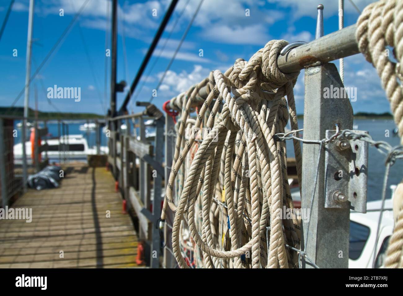 Corde di ormeggio attaccate a Un molo per barche che conduce al mare, Christchurch Harbour, Regno Unito Foto Stock