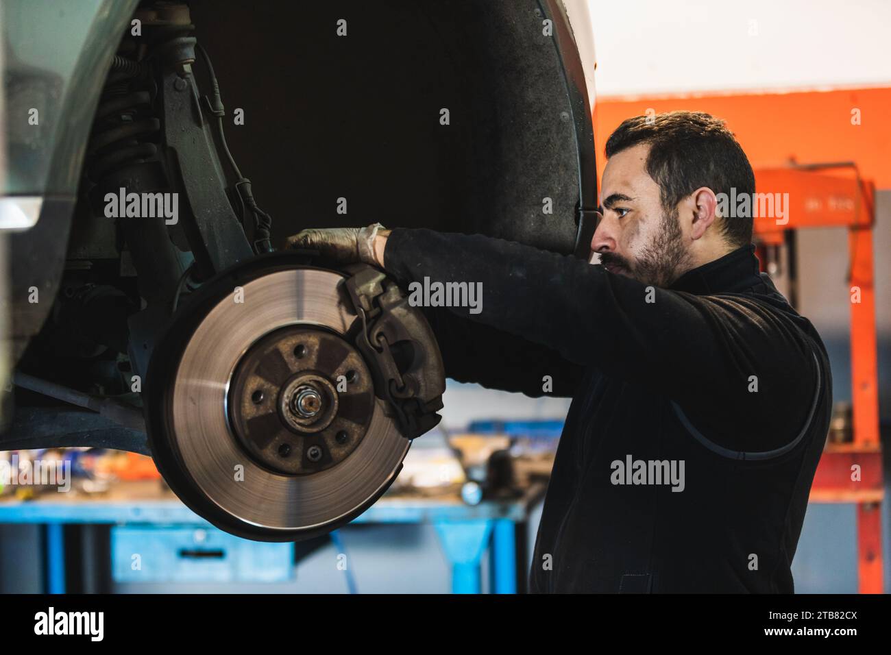 Meccanico che fissa i freni di un'auto nella sua officina Foto Stock