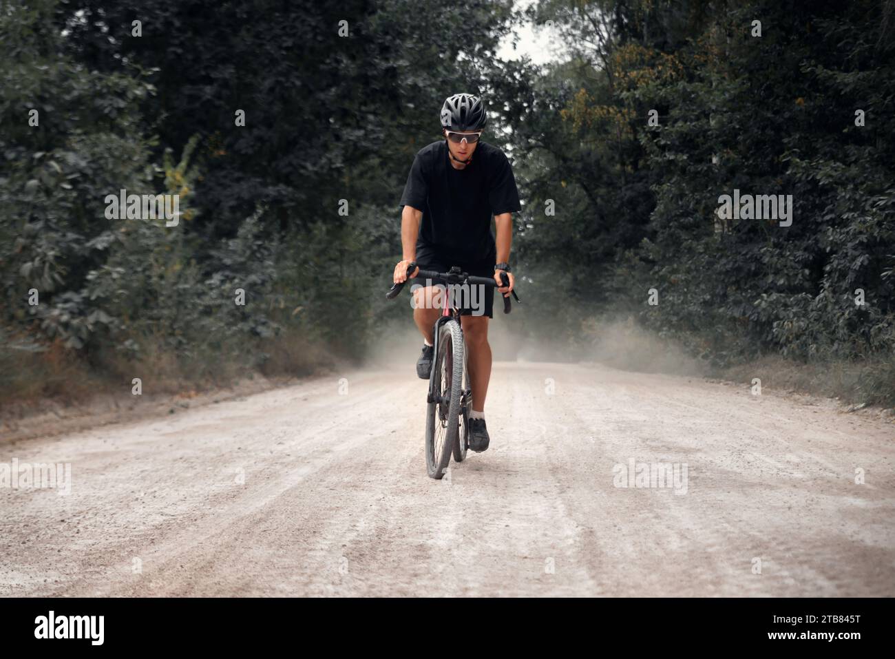 Il ciclista fa un giro in bicicletta nella foresta. Uomo in casco e bicchieri in bicicletta nella natura. Foto Stock