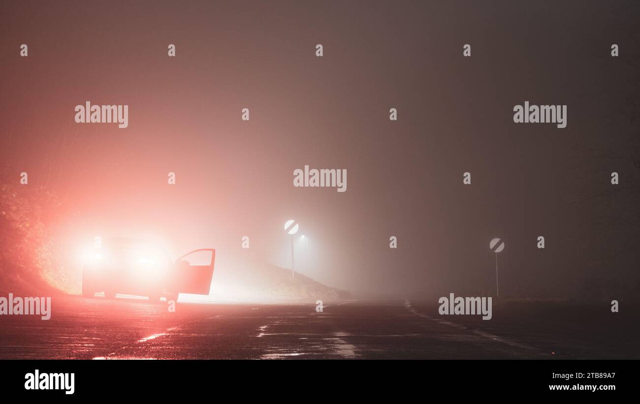 Un'auto parcheggiata con la porta aperta. Sul lato della strada. In una notte d'inverno spaventosa, inquietante, nebbia. Foto Stock