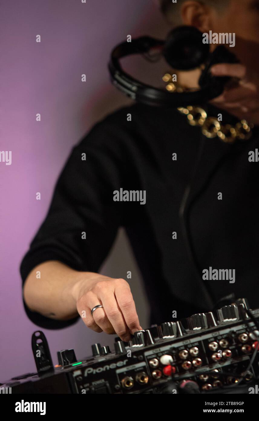 Set da festa DJ (disc jockey) con console di miscelazione Pionneer, maglietta nera e grande catena dorata. Primo piano di mani Foto Stock