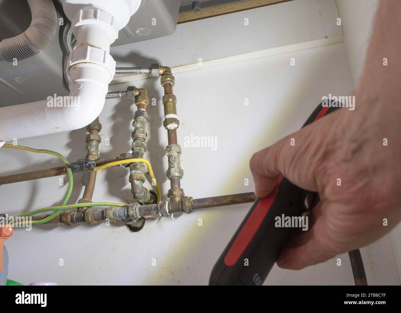 Uomo che utilizza una lampada a LED portatile o una torcia a LED per ispezionare l'impianto idraulico domestico Foto Stock