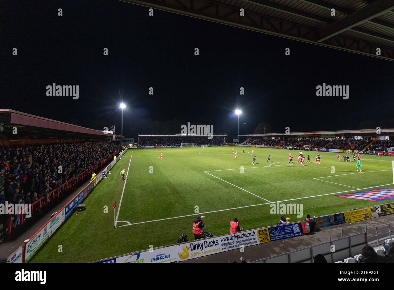 Vista dalla North Stand al Lamex Stadium, sede dello Stevenage Football Club sotto i riflettori durante la partita notturna. Foto Stock