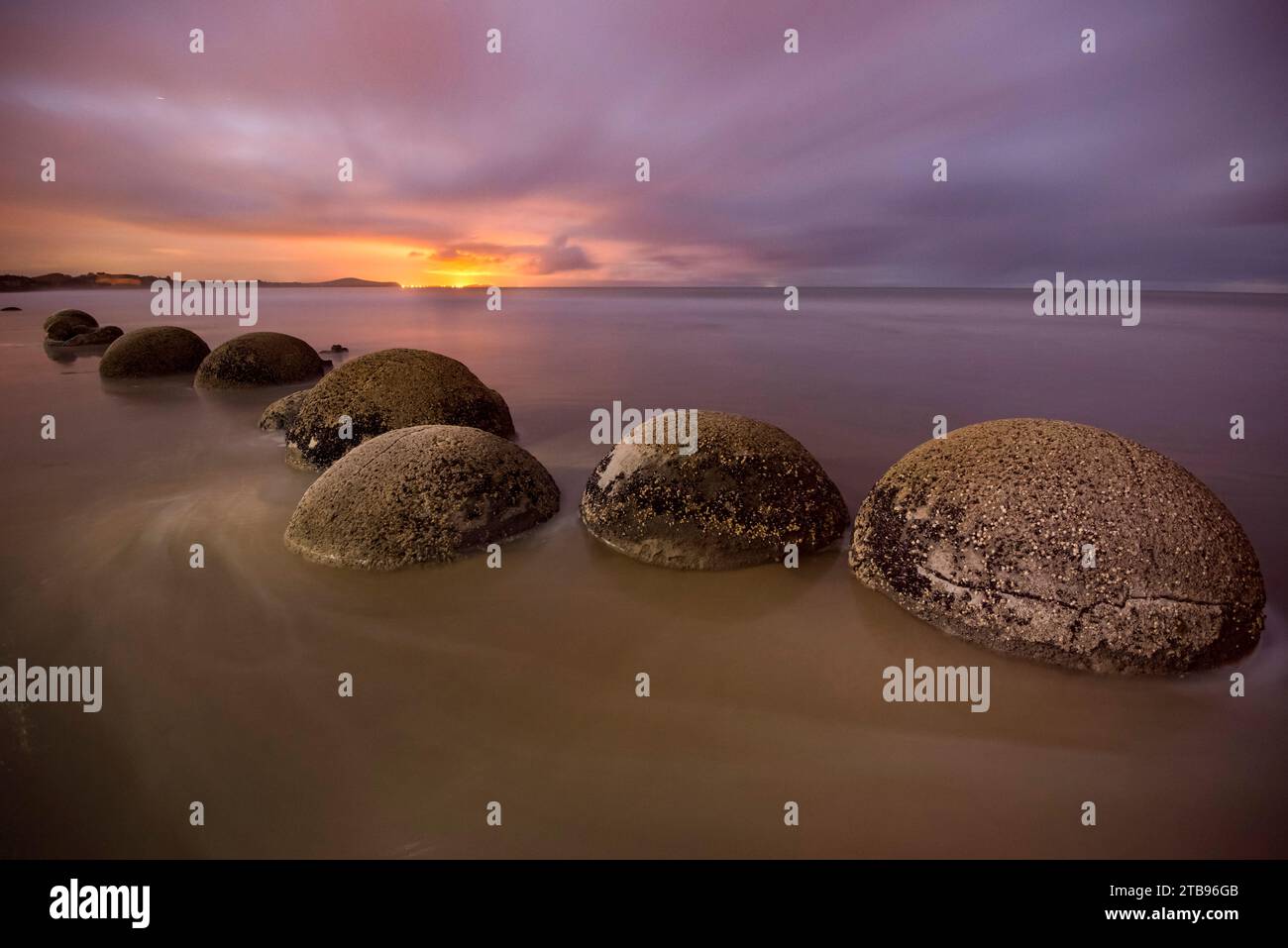 Moeraki Boulders illuminati lungo Koekohe Beach sull'isola meridionale della nuova Zelanda al crepuscolo; Hampden, North Otago, nuova Zelanda Foto Stock