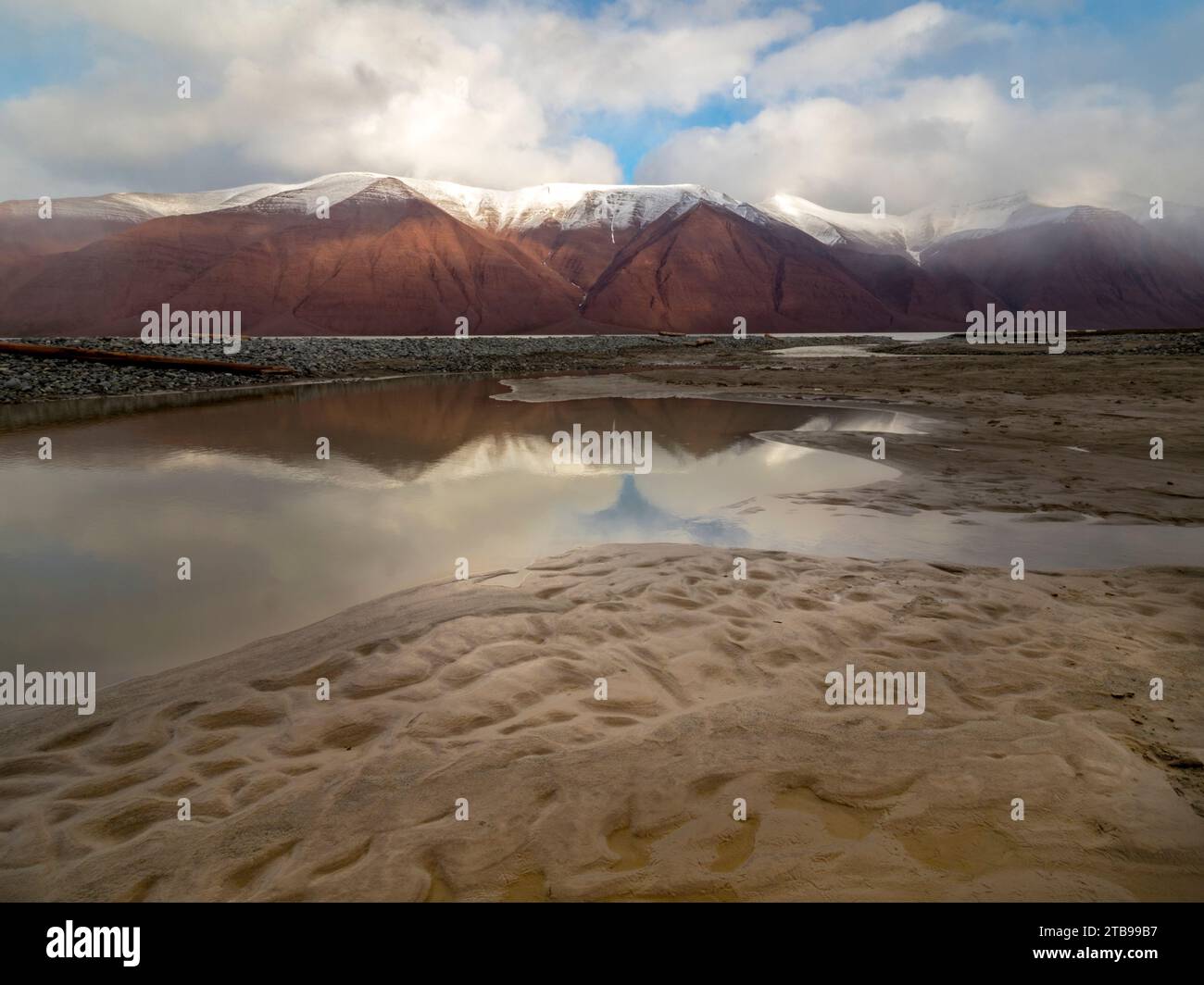 La piscina delle maree riflette una catena montuosa lontana; Spitsbergen, Svalbard, Norvegia Foto Stock