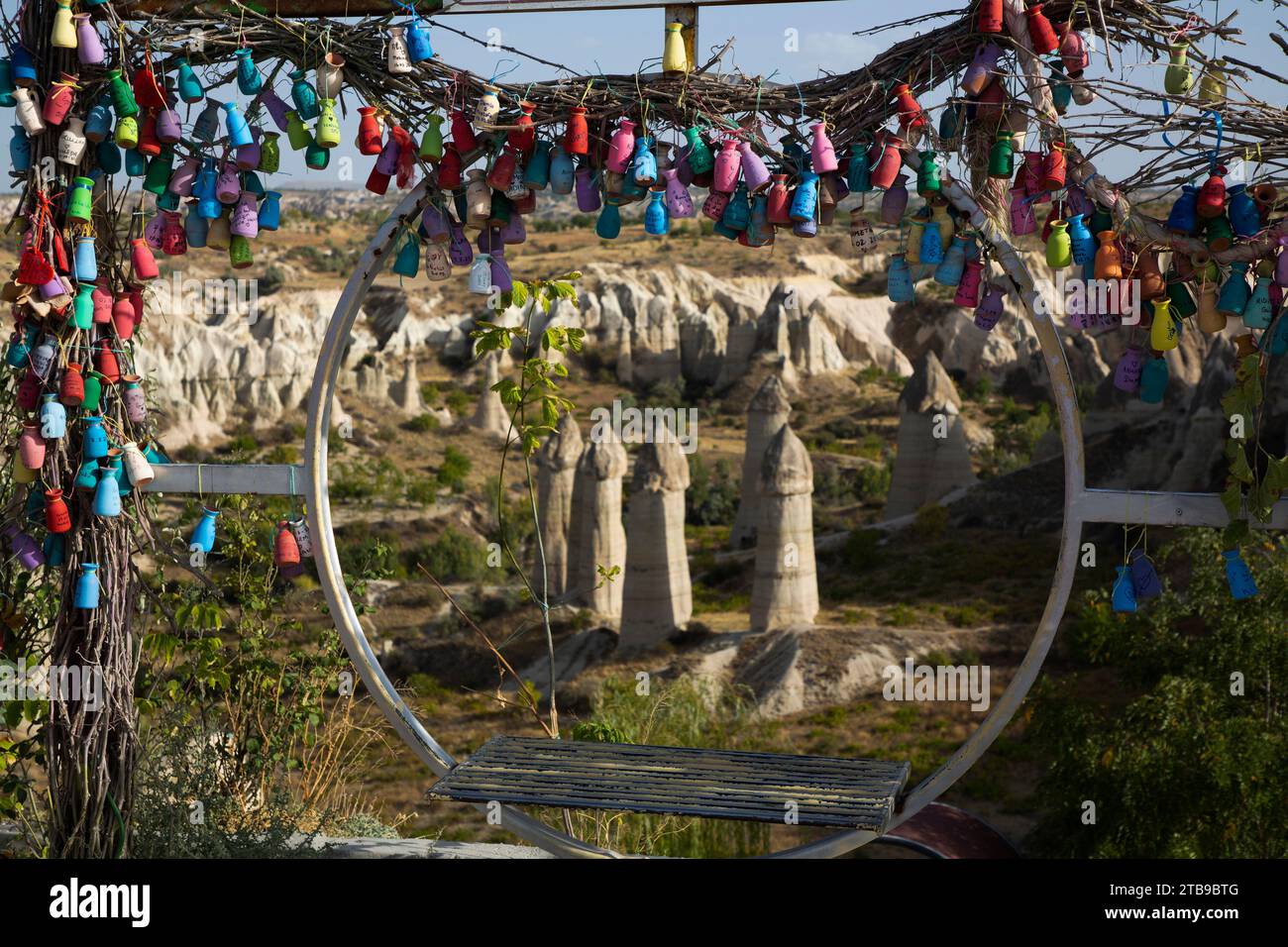 Vista attraverso una seduta circolare a dondolo decorata con vasi in ceramica colorata, delle formazioni rocciose di Fairy Chimney nella Love Valley vicino al... Foto Stock